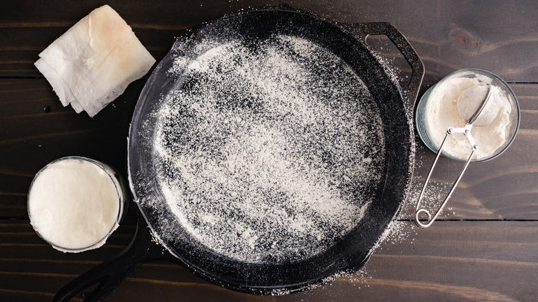 Flour heavily dusted on a greased cast iron skillet with a dark wood background