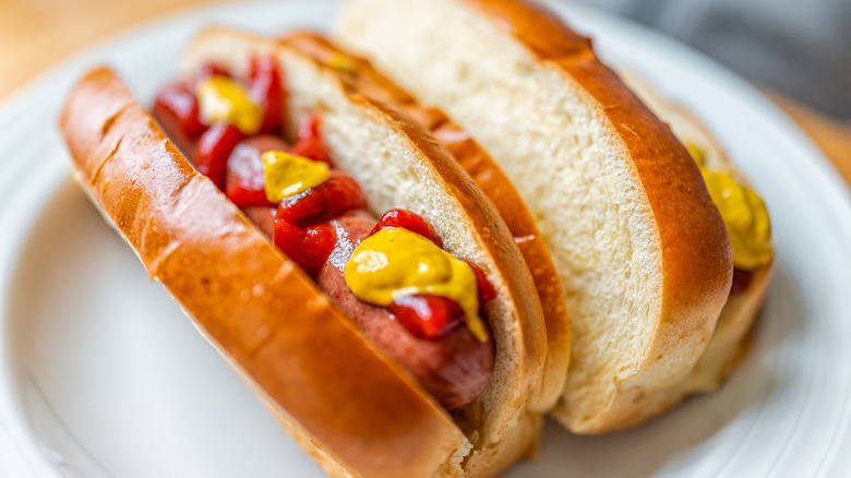 A hot dog in a brioche bun topped with mustard and ketchup.