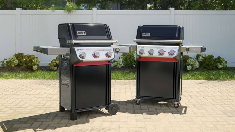 Two Weber gas grills sit on a patio.