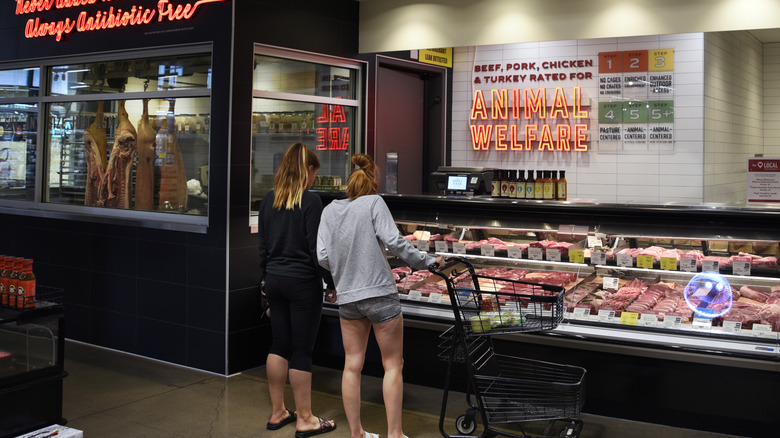 Two women examine meat in a Whole Foods cooler