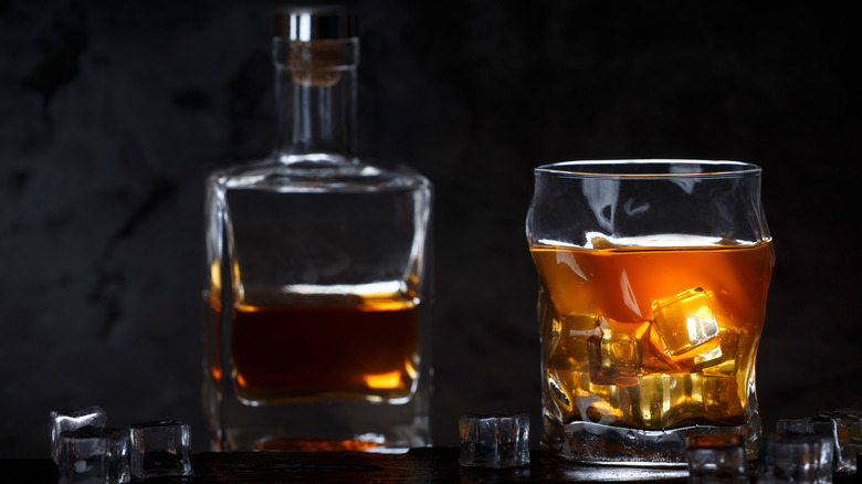 glass bottle full of whiskey next to a glass of whiskey