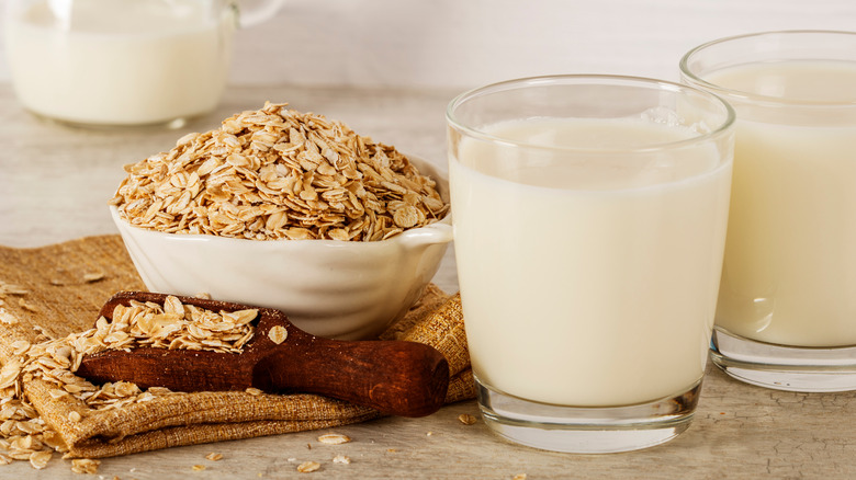 Bowl of oats and glasses of oat milk