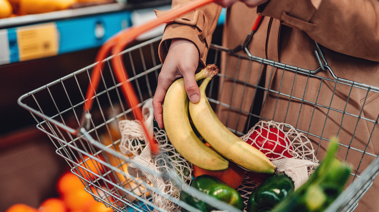 Shopper places bananas in shopping basket