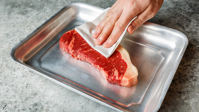 hand drying steak with paper towel