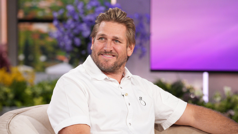 Curtis Stone smiling while sitting on a set