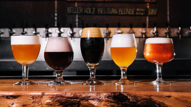 Various beers in glasses on a bar shelf