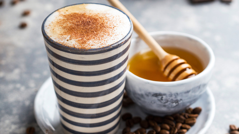 Coffee latte next to bowl of honey