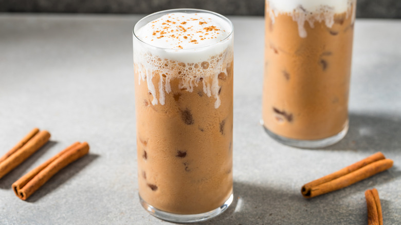 Iced latte served in glass with cold foam and a sprinkle of cinnamon on top.