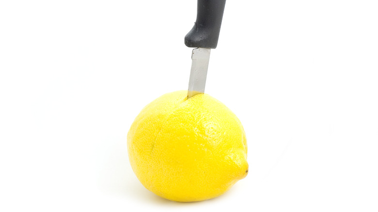 A knife stabbing a lemon