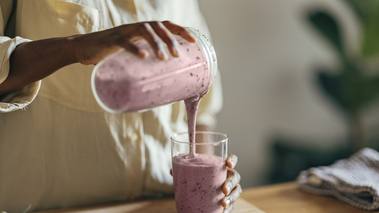 Person pouring a smoothie into a glass