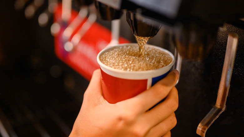 Hand getting soda in cup from a fountain drink machine