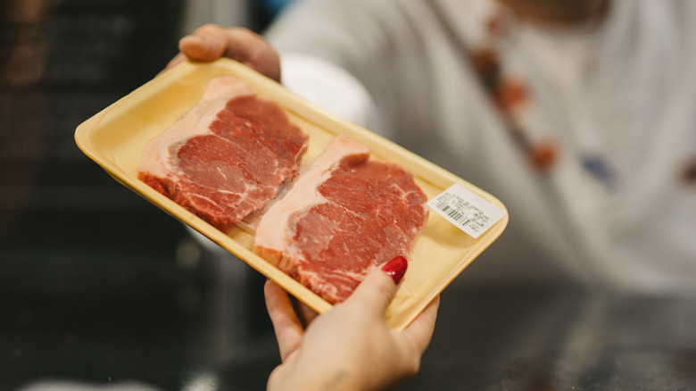 woman purchasing steak from butcher