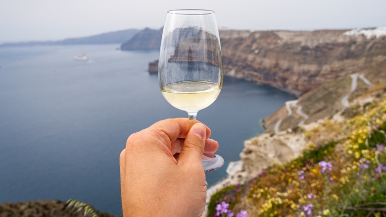 Glass of Assyrtiko wine against ocean backdrop