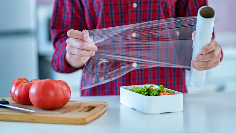 hands pulling roll of plastic wrap