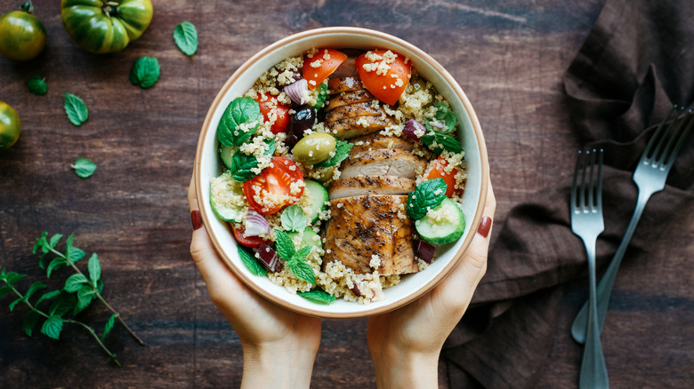 A woman's hands holding a bowl with mixed salad inside