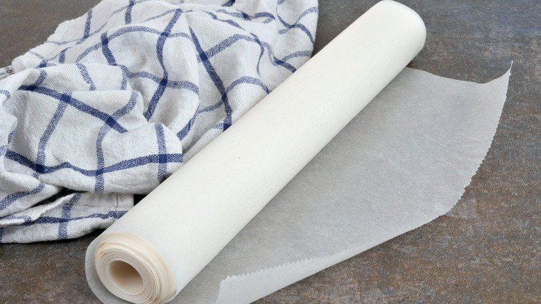 Roll of wax paper pan liner on counter with blue and white kitchen towel