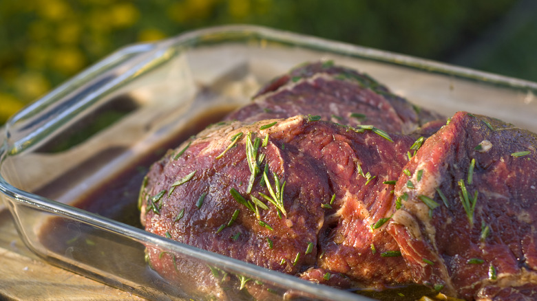 Steaks marinating in a glass dish.