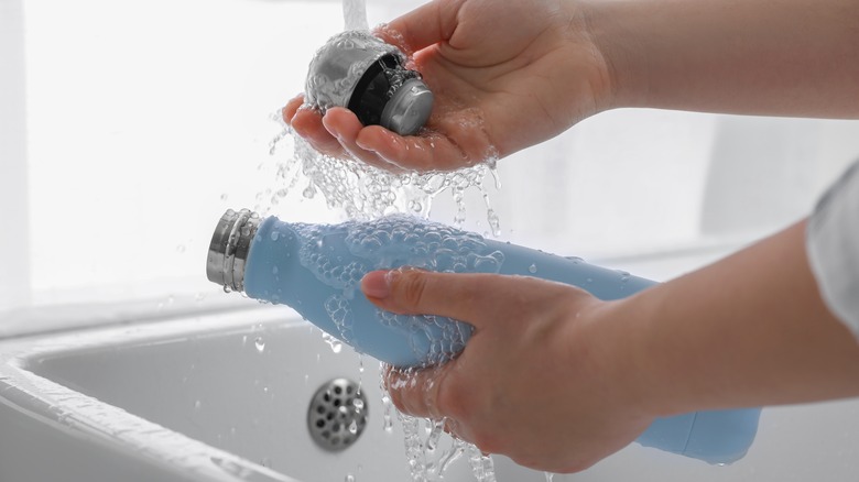 Cleaning blue thermos in sink 