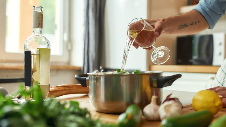 adding white wine to pot while cooking