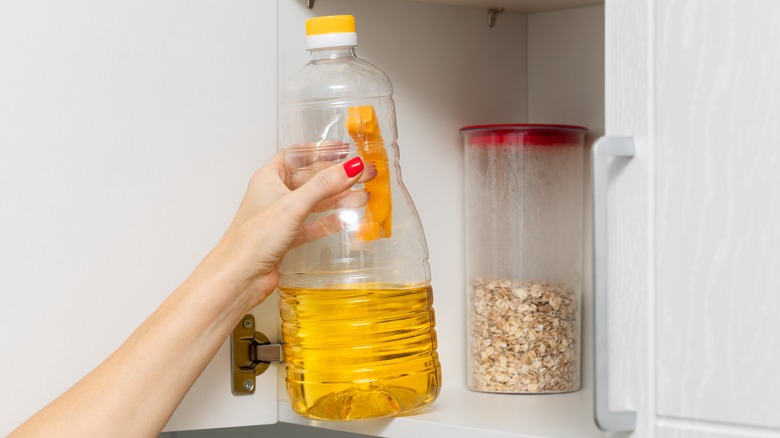 Woman taking olive oil from cabinet