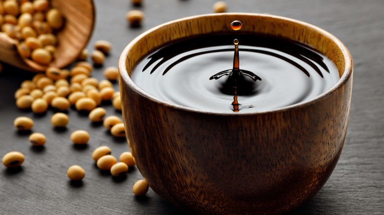 Bowl of soy sauce with soybeans in the background