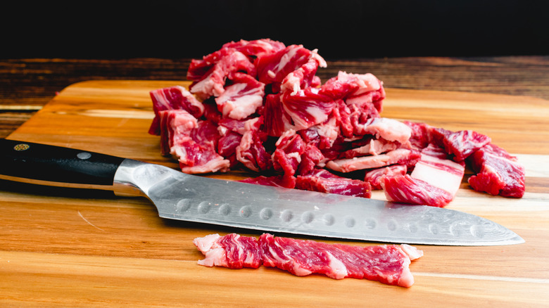Thinly sliced beef on wooden cutting board