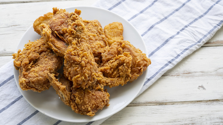 A plate of fried chicken sits on a white cloth with blue stripes.