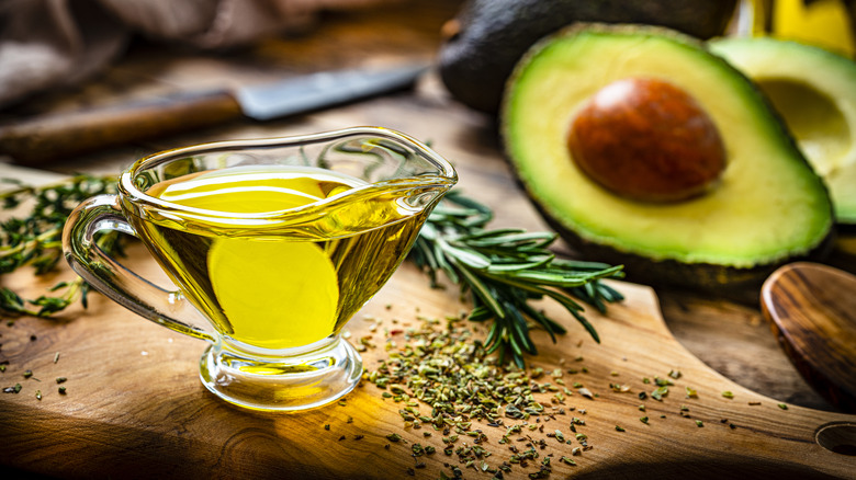 Avocado oil in glass container  with cut avocado 