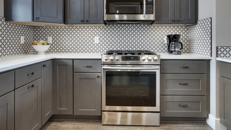 A beautifully tiled backsplash adorns a gray kitchen.