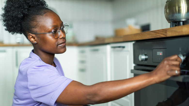A homeowner turns the knob on an oven.