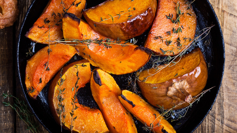 baked squash on a roasting tray with fresh herbs