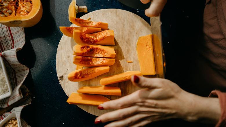 woman slicing a Butternut Squash on a wooden cutting board