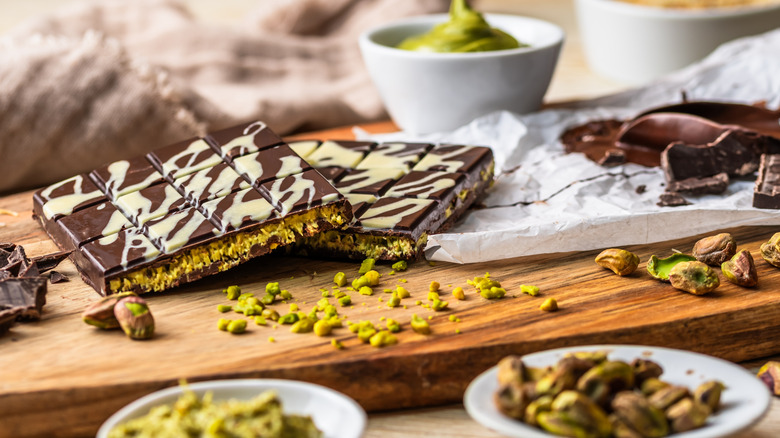 Homemade Dubai chocolate with a white chocolate accent on a cutting board with crushed pistachios
