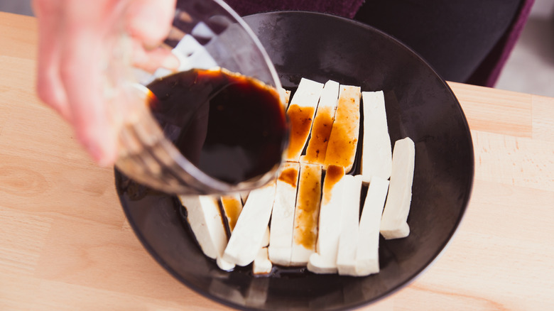 Person pouring tofu marinade in a bowl
