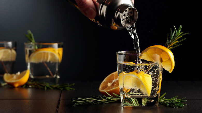 Drink being poured in a glass with lemons