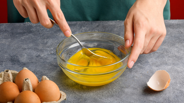 Eggs being scrambled in bowl with a fork
