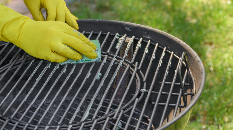 A person cleaning a dirty barbecue.