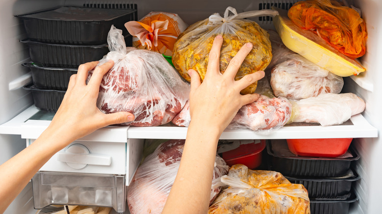 Hands arranging frozen food in a freezer for storage