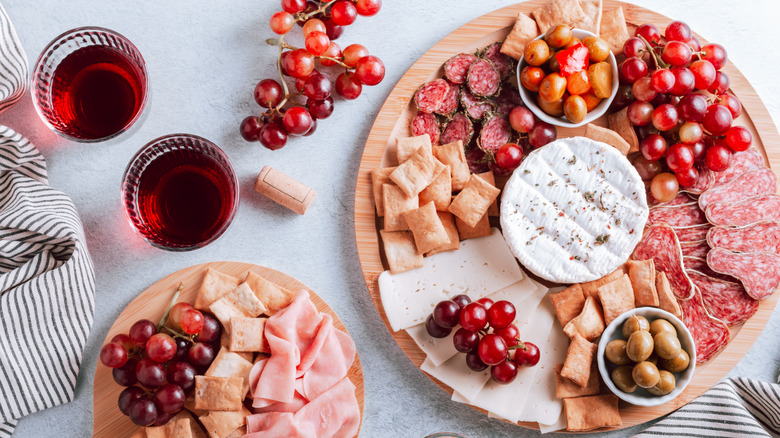 Various cheeses and fruit on wooden board