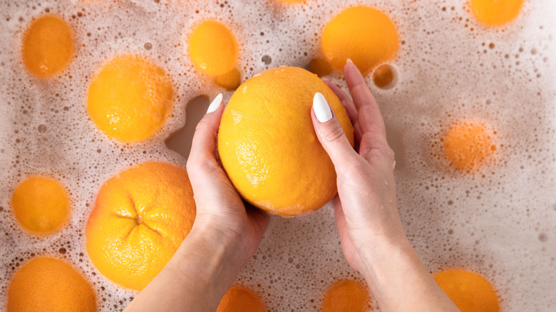 Person washing orange in sink