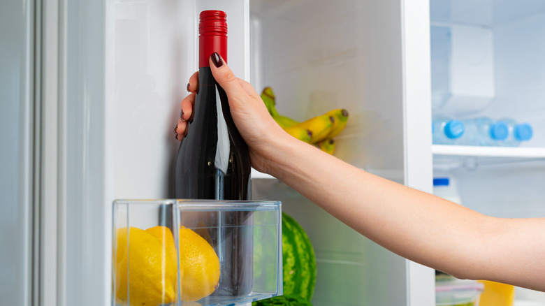 Hand grabbing wine bottle from fridge