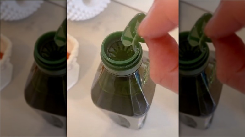 pulling pull tab off olive oil bottle