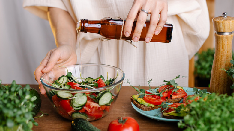 pouring olive oil over salad