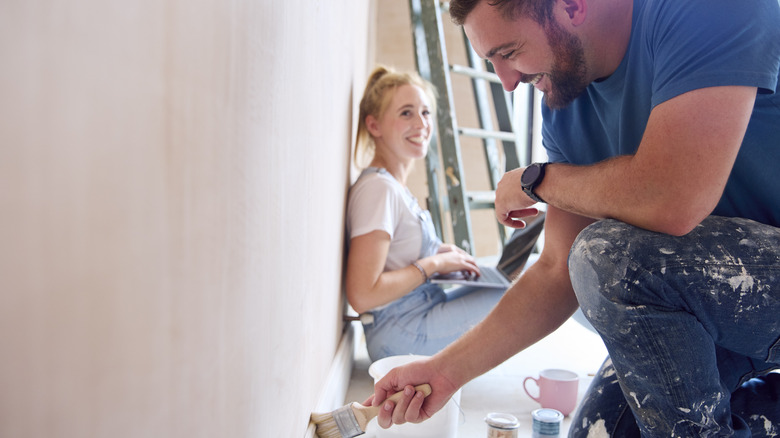 A couple renovating a room in their home, painting