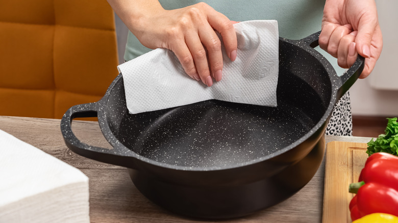 Person holding cast iron pan with paper towel.