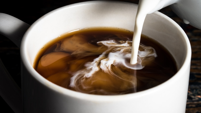 cream being poured into cup of coffee