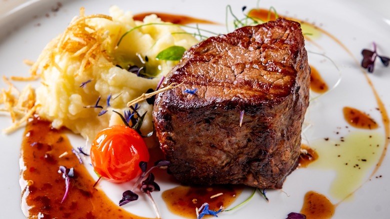 filet mignon with mashed potatoes and steak sauce on a plate