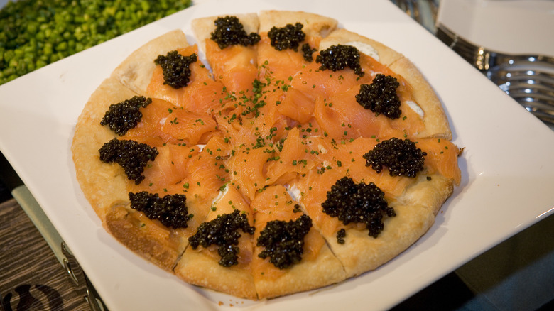 Pizza with salmon and caviar on a square white plate