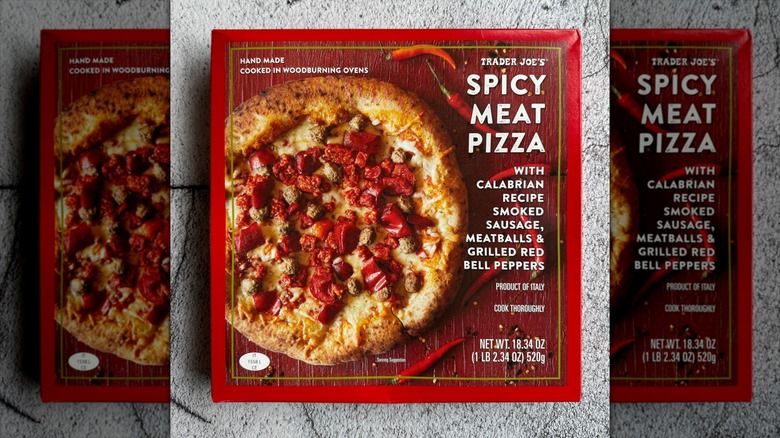 A box of Trader Joe's Spicy Meat Pizza sits on a kitchen counter