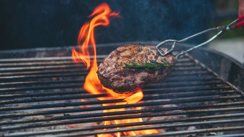 Flame flaring up from grill onto a cooking steak